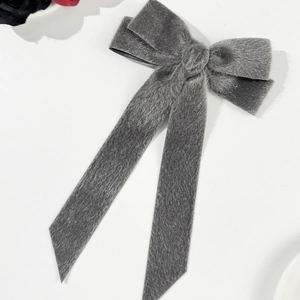 Detail of plush grey bow hair clip with long ribbons and soft velvet texture