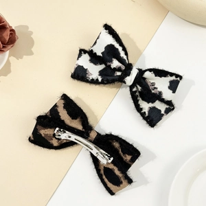 Detail of leopard and cow print bow hair clips with silver metal spring fasteners
