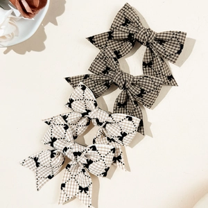 Gros plan de quatre barrettes à carreaux marron et beige avec motifs de papillons