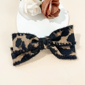 Close-up detail of leopard print bow hair clip with plush faux fur edges on fabric
