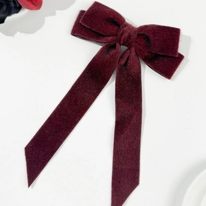 Close-up of deep red velvet bow hair clip with long ribbons and premium texture