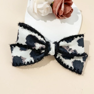 Detail of cow print bow hair clip with black faux fur trim on a decorative plate