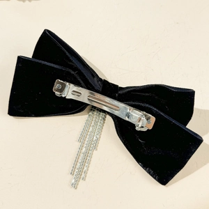 Detail of black velvet bow hair clip with silver spring clasp and rhinestone tassels