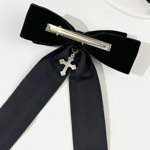 Detailed close-up of a black velvet gothic bow hair clip with a silver cross pendant
