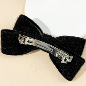 Detailed view of black velvet bow hair clip with silver metal spring fastener and texture