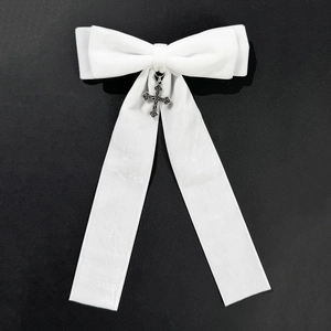 Close-up of white satin bow hair clip with vintage silver gothic cross and long ribbons