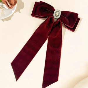 Close-up of burgundy velvet bow hair clip with vintage rhinestone center and long ribbons