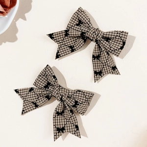 Détail de barrettes à cheveux à nœud écossais marron avec motifs noirs et rubans