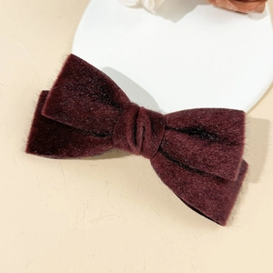 Close-up of a burgundy plush velvet bow hair clip with elegant textured finish