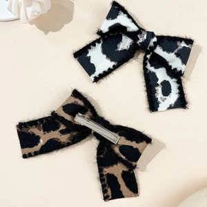 Detail of leopard print bow hair clips with soft fabric texture and metal duckbill grip