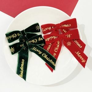 Gros plan de nœuds de Noël en velours avec inscription dorée Merry Christmas et étoiles