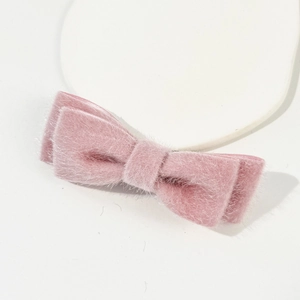 Détail d'une pince à cheveux nœud en peluche rose doux avec texture en fausse fourrure