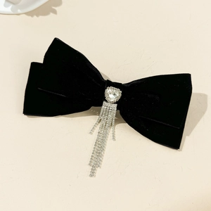Close-up of black velvet bow hair clip featuring a sparkling rhinestone heart and tassels