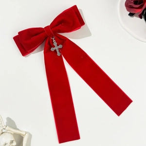 Detail of red velvet bow hair clip with silver gothic cross pendant and long ribbons