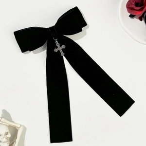 Close-up of black velvet bow hair clip with silver cross pendant and dark gothic aesthetic
