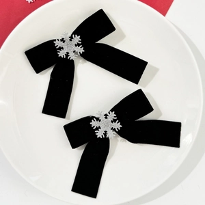 Détail de pinces à cheveux en velours noir avec flocons de neige argentés pour Noël
