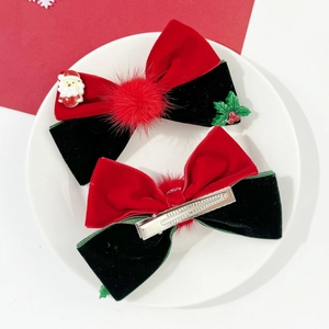 Detailed view of red and green velvet Christmas hair clips with Santa and bell accents