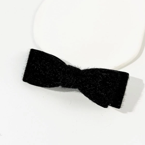 Détail d'un nœud papillon en peluche noire avec bande élastique blanche pour la coiffure
