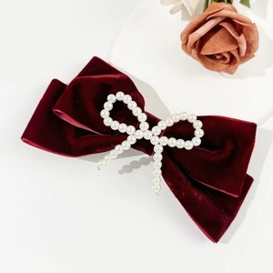 Detail of burgundy velvet hair clip with white pearls in an elegant bow design