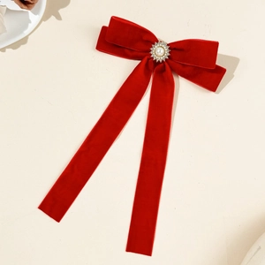 Close-up of red velvet bow hair clip with central pearl and crystal sunburst detail