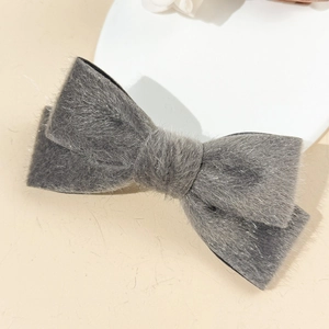 Detail view of a gray plush bow hair clip featuring soft texture and fine fuzzy material