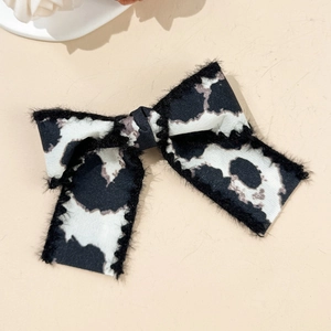 Close-up of leopard print bow hair clip with black plush edges and soft fabric texture