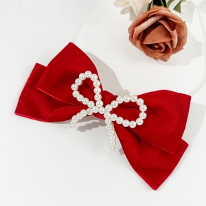 Detailed macro view of an elegant red velvet bow hair clip with white pearl butterfly center