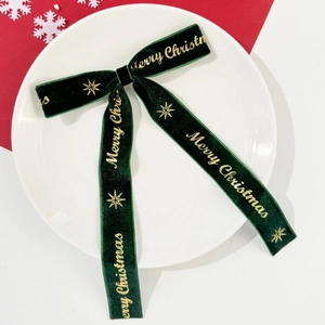 Détail du nœud en velours vert foncé avec lettrage doré Merry Christmas et étoiles