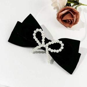 Elegant black velvet hair clip featuring a retro pearl bow design on a white surface