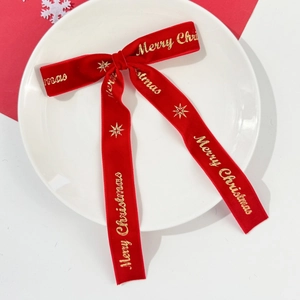 Détail d'un nœud de Noël en velours rouge avec l'inscription dorée Merry Christmas