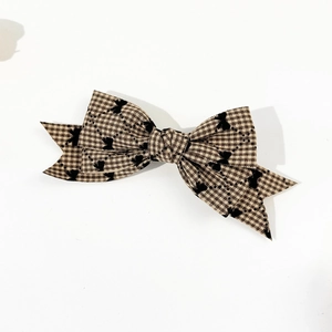 Détail d'un nœud à cheveux à carreaux marron avec motif papillon et coupe en queue d'aronde