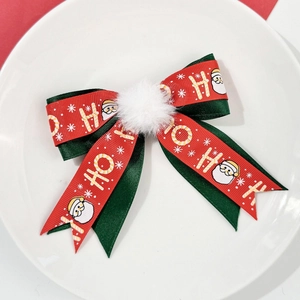 Détail de la pince à cheveux nœud de Noël avec imprimé HO HO HO et pompon blanc