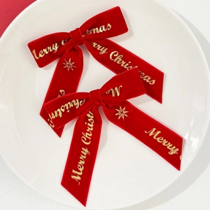 Détail de deux barrettes de Noël en velours rouge avec imprimé doré Merry Christmas
