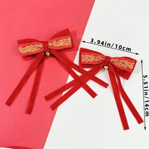 Detail of red velvet Christmas bow with gold embroidery and metal bell measuring 10x14cm