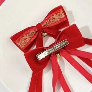 Detail of red velvet Christmas hair bow clips with bells and long ribbon tassels