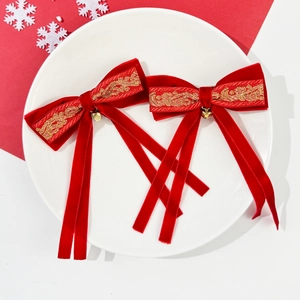 Close-up of red velvet Christmas bow hair clips with golden bells and embroidery