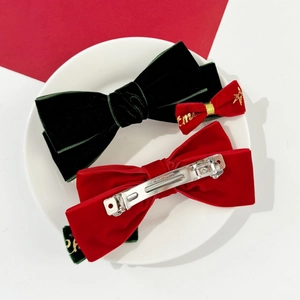 Détail de barrettes à nœuds de Noël en velours avec broderie dorée et clip à ressort en métal