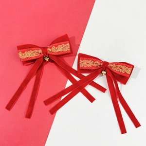 Detail of red velvet Christmas bow hair clips with gold embroidery and metal bells