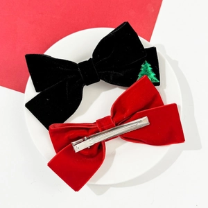 Detail of red and black velvet Christmas bow hair clips with festive tree charms