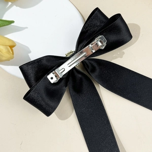 Close-up of black silk ribbon bow hair clip with silver metal spring buckle on back
