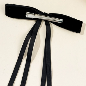 Detail view of the silver metal alligator clip and back structure on black velvet bow