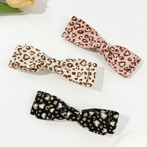 Three leopard print heart bow hair clips in pink, cream and black on white background