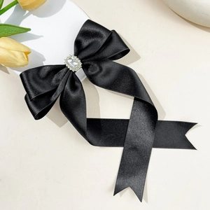 Detailed view of elegant black satin bow hair clip with sparkling rhinestone centerpiece