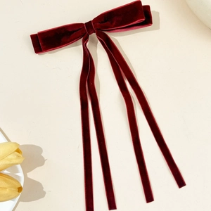 Detail of elegant dark burgundy velvet bow hair clip with four long hanging streamers