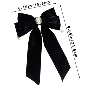Detail of black velvet bow hair clip showing elegant pearl center and gold rimmed accents