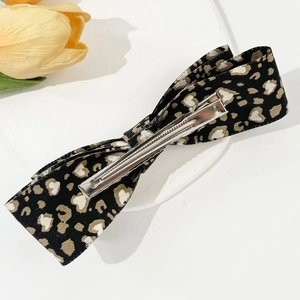Detail of leopard print bow hair clip featuring a secure silver metal duckbill clamp back