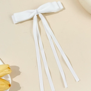 Detail of elegant white double-layered bow hair clip with long satin ribbons for women