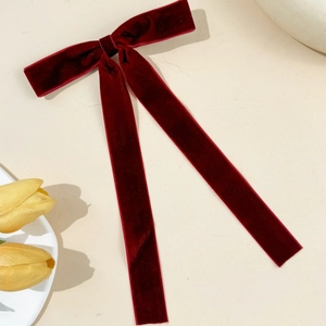 Macro detail of wine red velvet bow hair clip with long flowing ribbon streamers