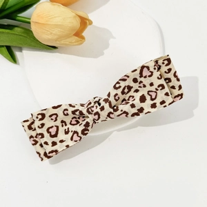 Close-up of leopard print bow hair clip with pink hearts on a ceramic display tray