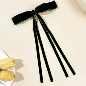 Detail of dark green velvet bow hair clip with long ribbons and smooth texture